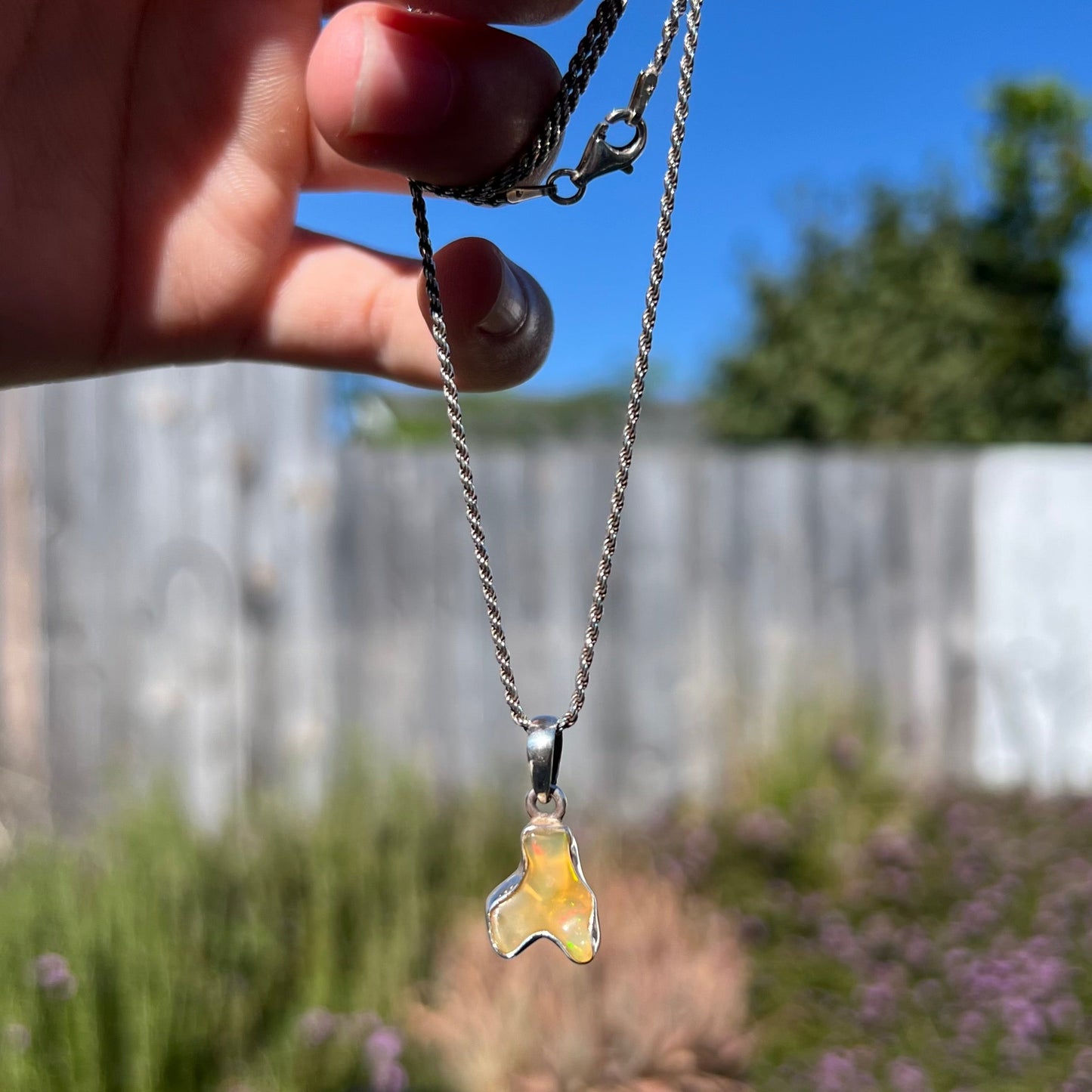 A freeform shaped Mexican fire opal necklace on a sterling silver rope chain.
