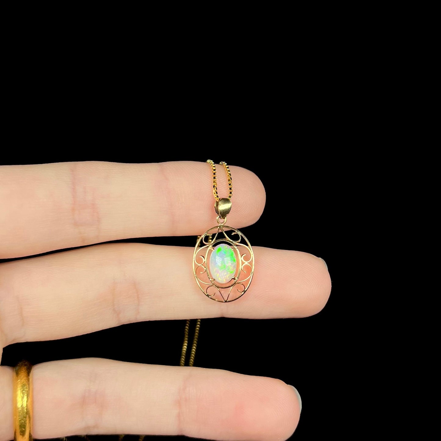 An 18 karat yellow gold filigree opal necklace. The opal has bright green color play.