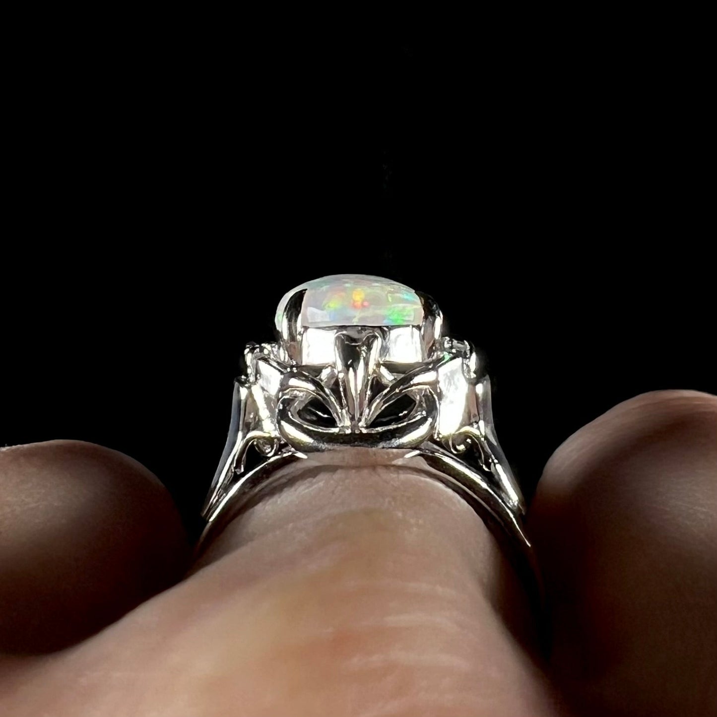 A platinum and diamond ring prong-set with an Australian opal. The opal has pink color play.
