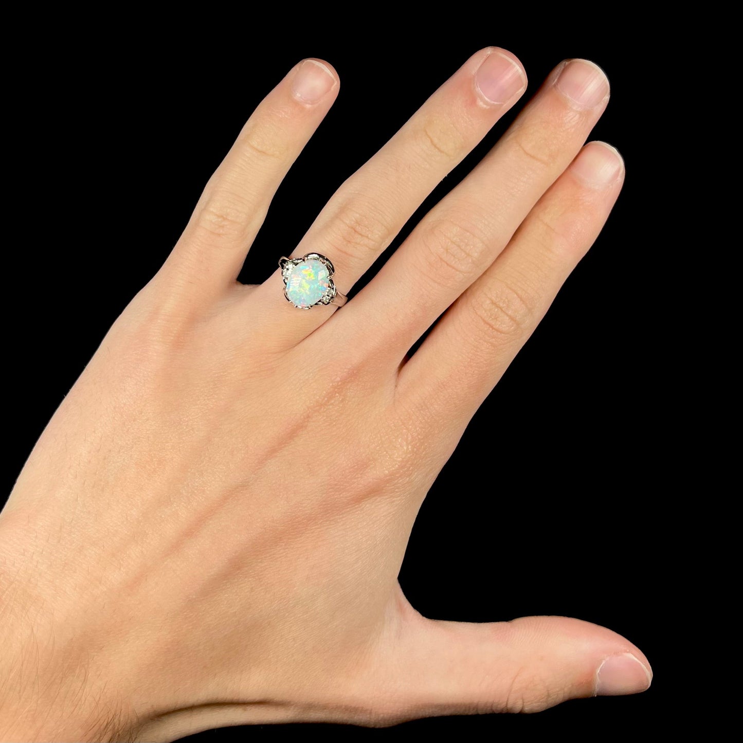 A platinum and diamond ring prong-set with an Australian opal. The opal has pink color play.