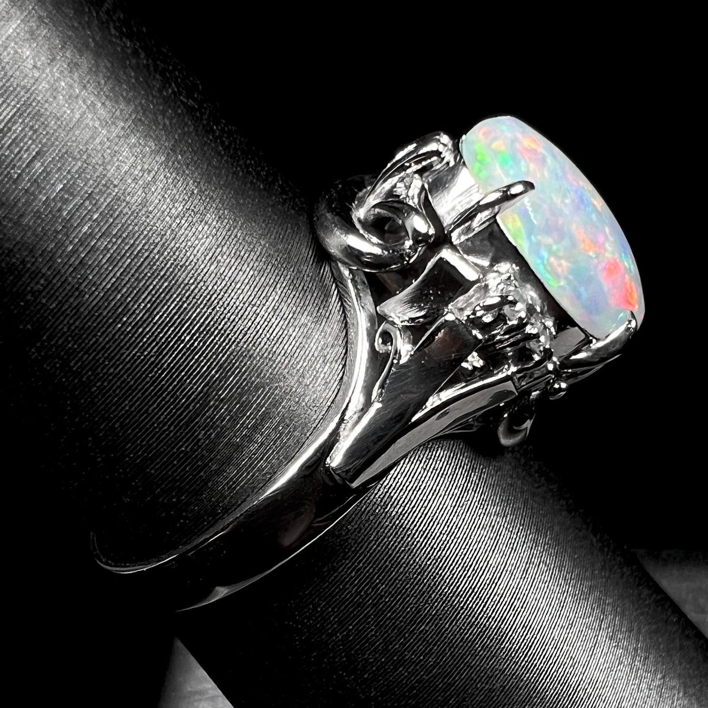 A platinum and diamond ring prong-set with an Australian opal. The opal has pink color play.