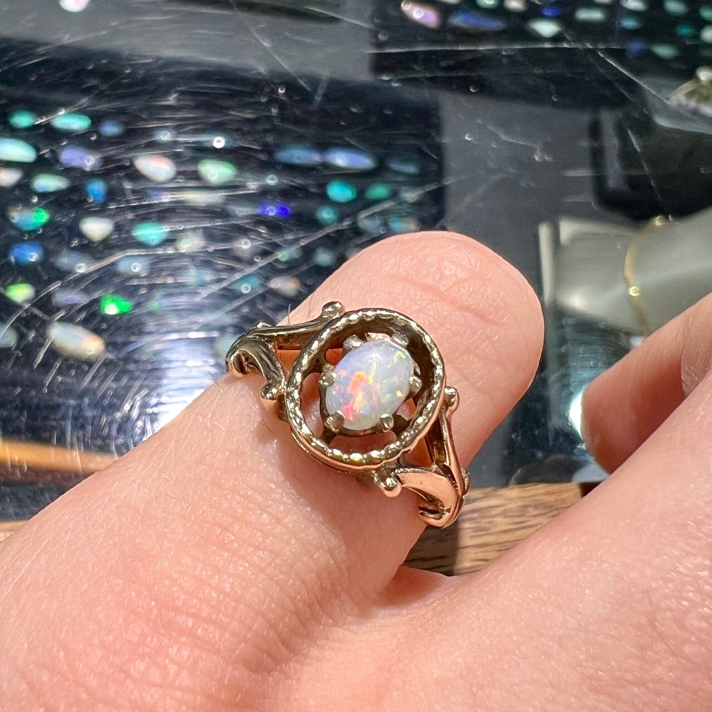 A ladies' Art Nouveau style opal solitaire ring. The mounting is yellow gold with filigree accents.