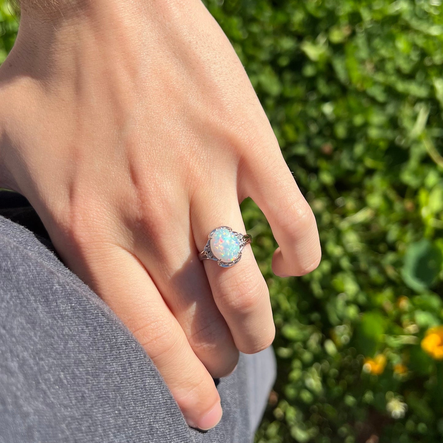 A platinum and diamond ring prong-set with an Australian opal. The opal has pink color play.