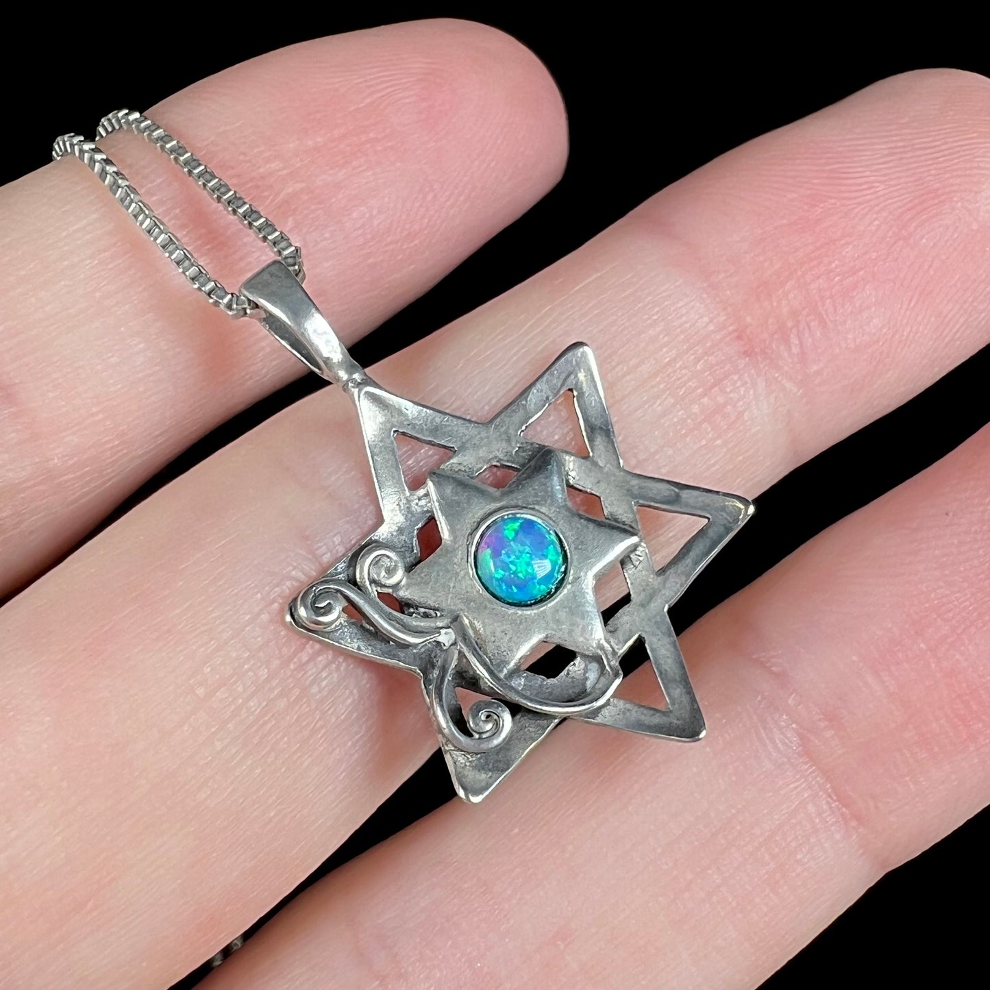 A sterling silver Star of David necklace set with a round blue lab-created opal.