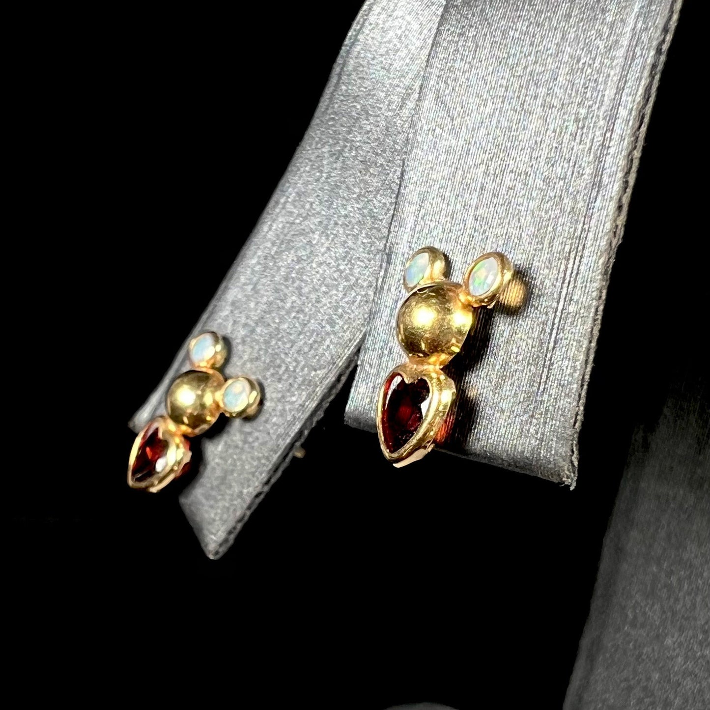 A pair of 18 karat yellow gold stud earrings set with two round fire opals and heart shaped garnets.