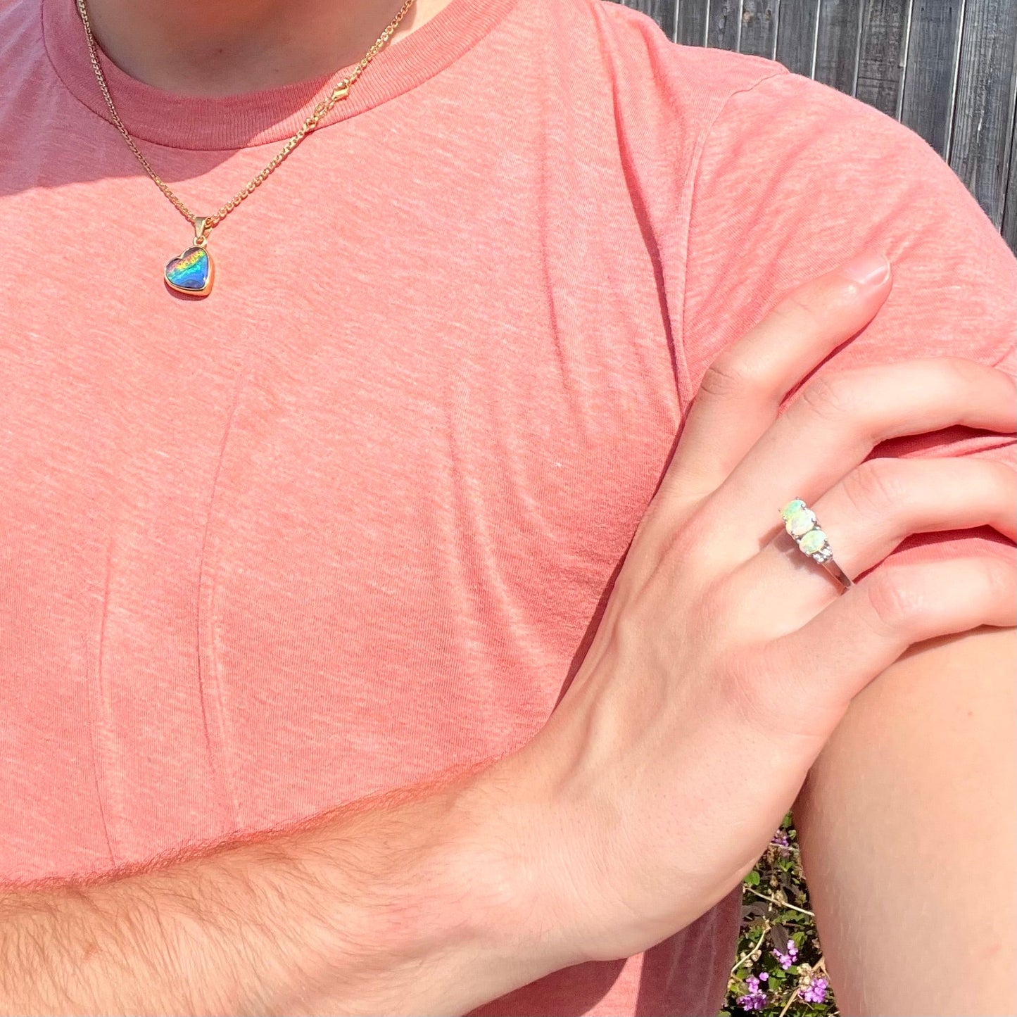 A ladies' white gold ring prong-set with three natural white opals and diamond accents. The opals play a green color.