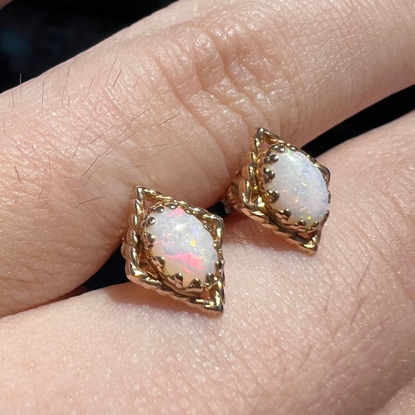 A pair of opal stud earrings. The opals are set in yellow gold diamond shaped mountings.