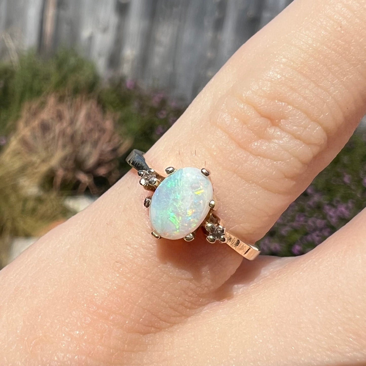 A dainty, 1960's style opal and diamond engagement ring. The ring is prong-set and yellow gold.