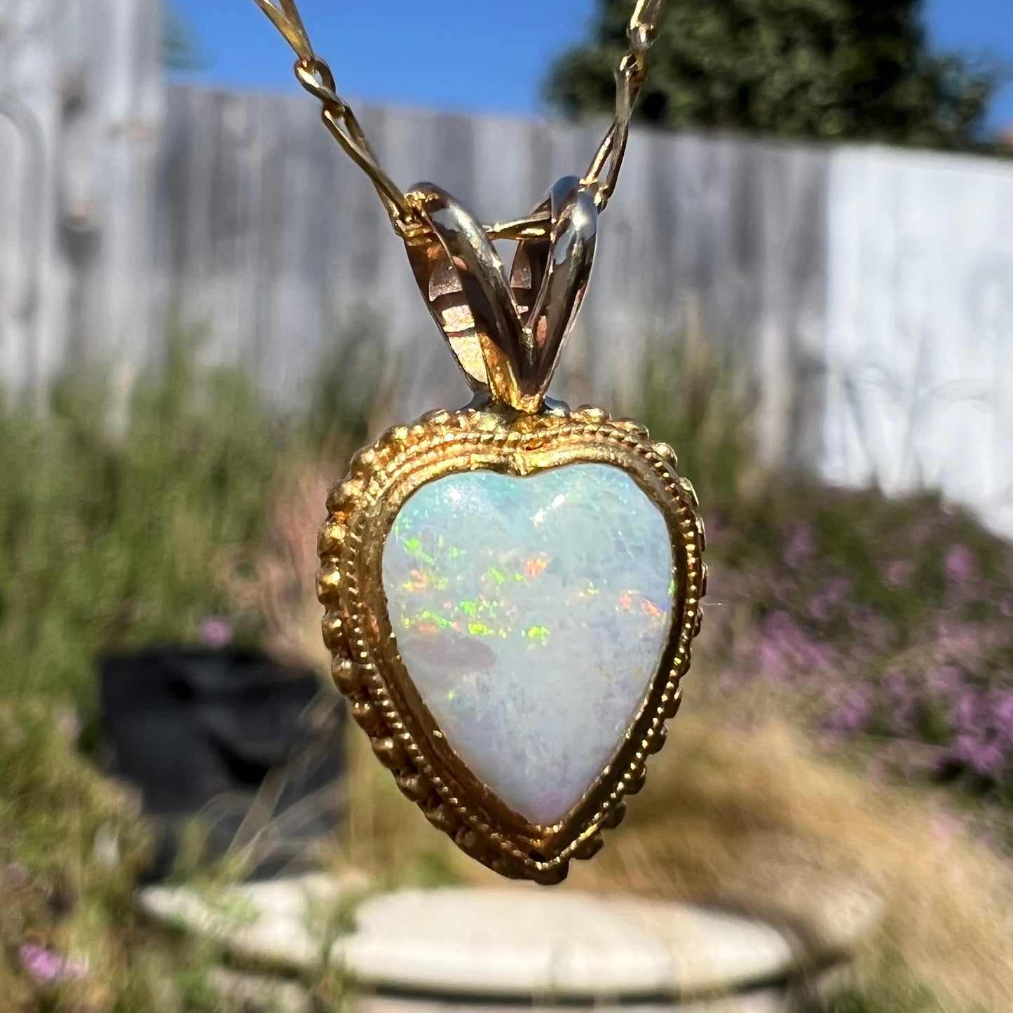 A yellow gold heart necklace mounted with a heart shaped white opal.