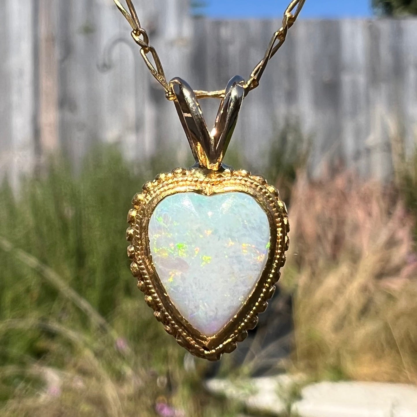 A yellow gold heart necklace mounted with a heart shaped white opal.