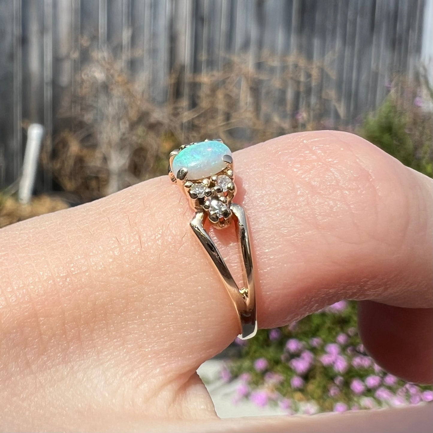 A ladies' yellow gold opal and diamond pinkie ring. The ring is a small size, and the opal shines green and blue colors.