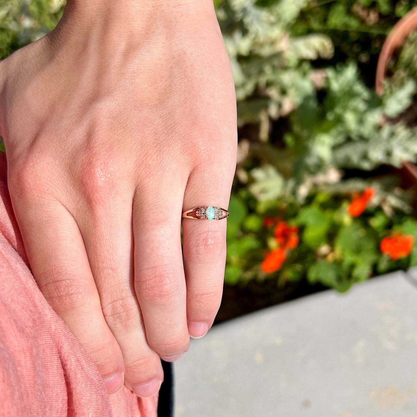 A ladies' yellow gold opal and diamond pinkie ring. The ring is a small size, and the opal shines green and blue colors.
