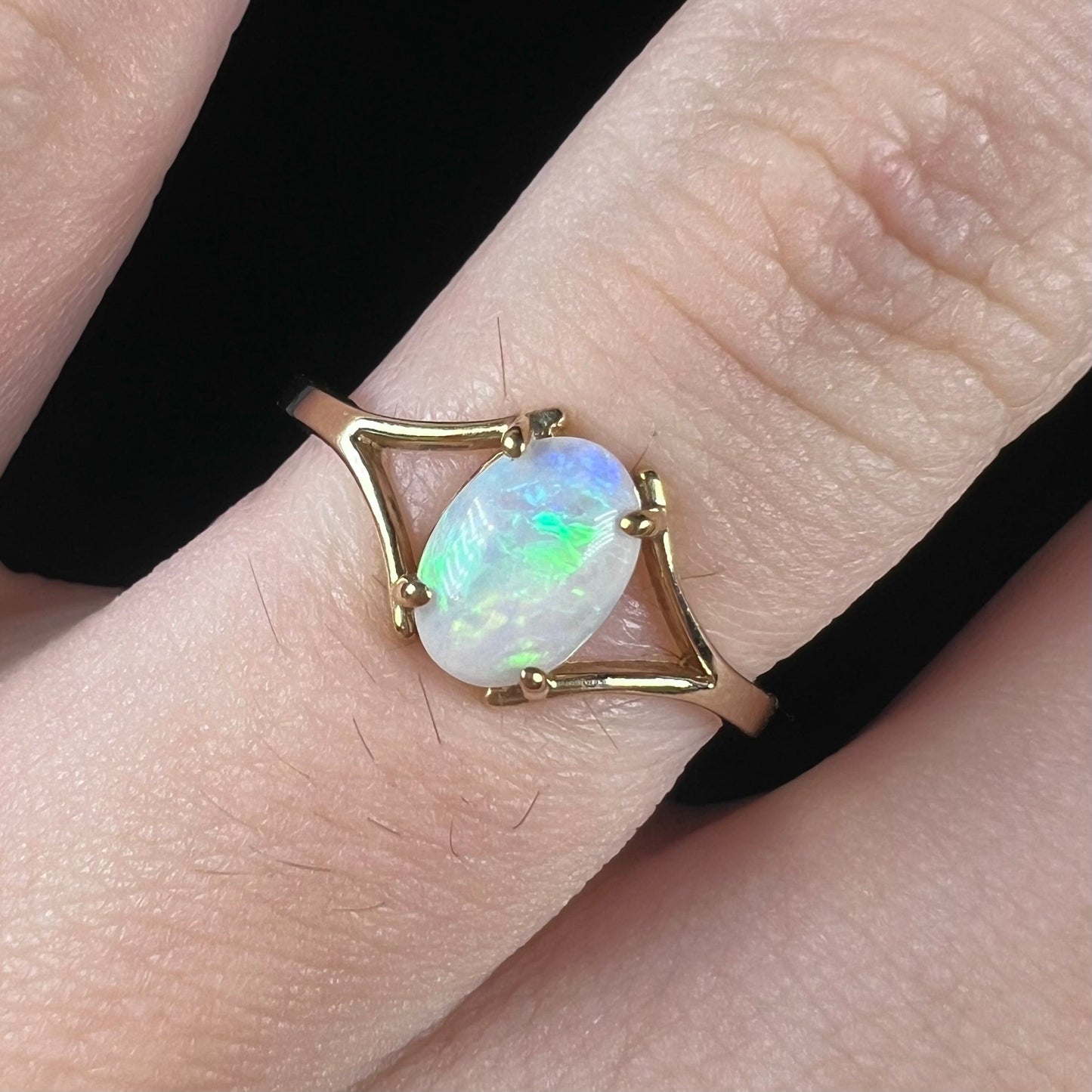 A ladies' simple opal solitaire ring. The ring is yellow gold with a split shank.