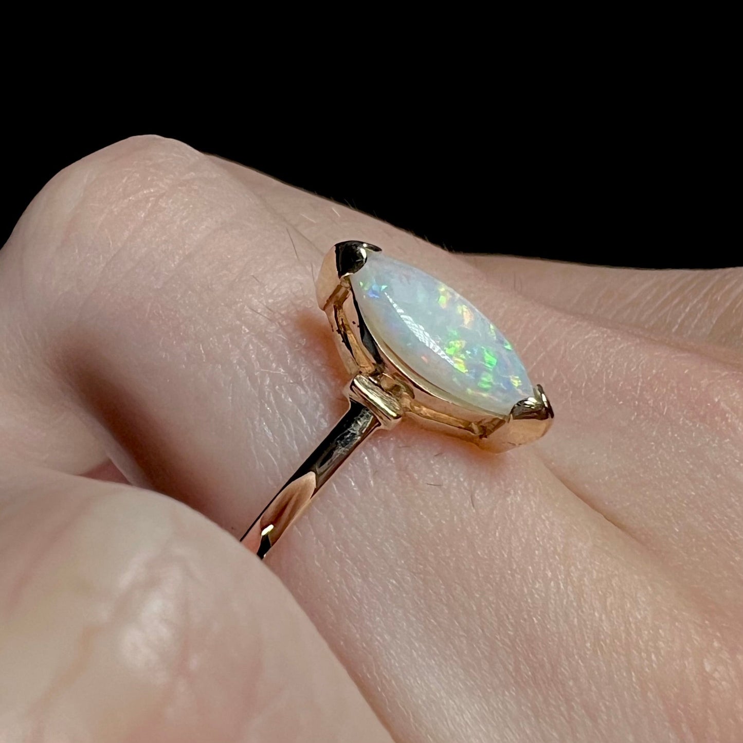 A marquise cut natural opal solitaire ring in yellow gold.