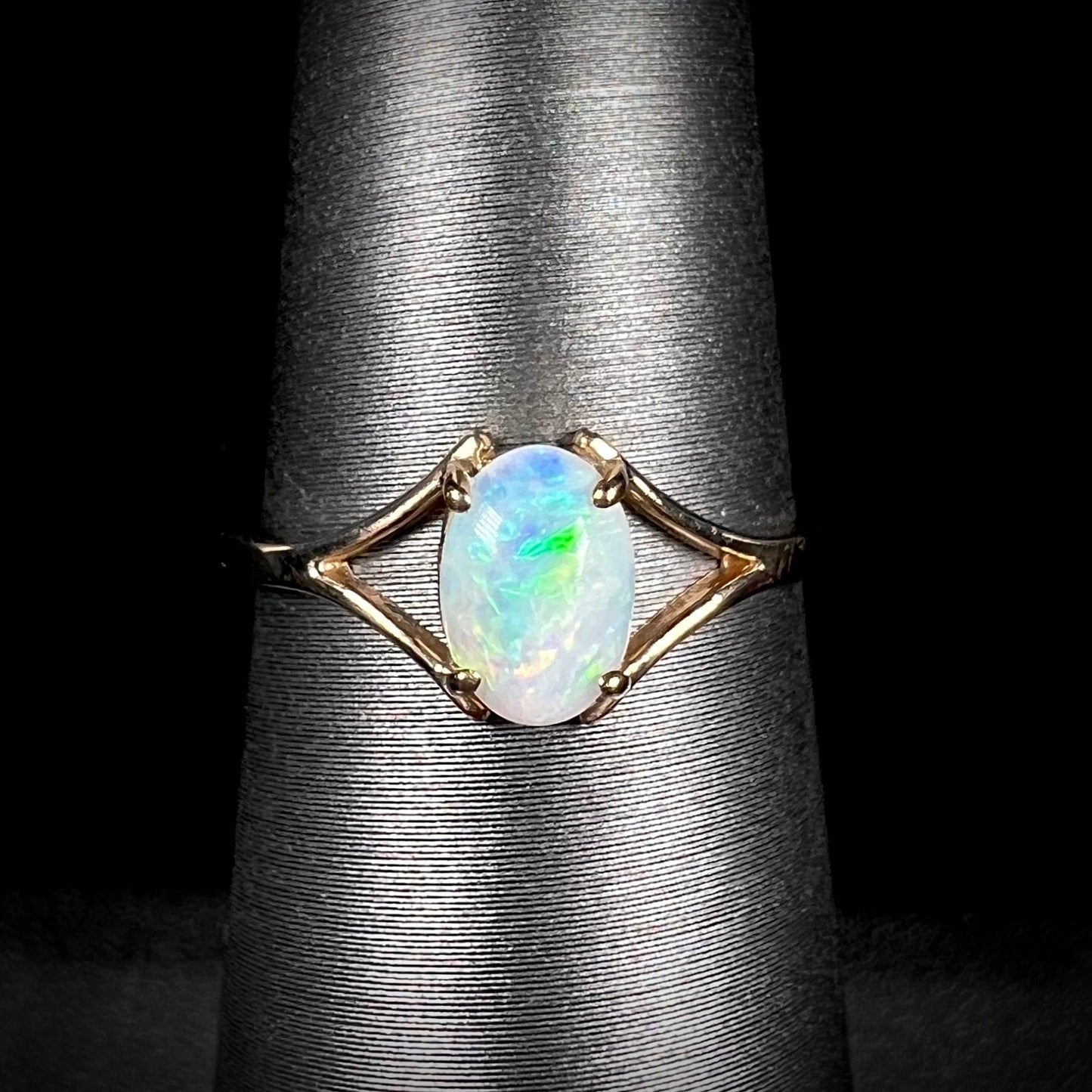 A ladies' simple opal solitaire ring. The ring is yellow gold with a split shank.