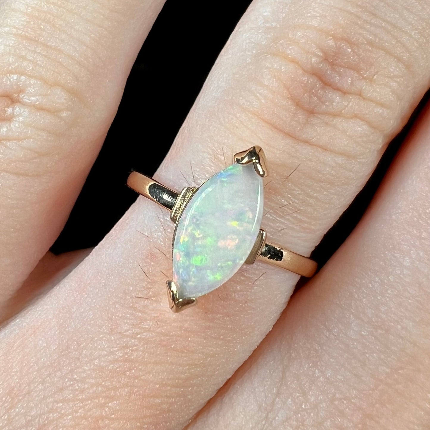 A marquise cut natural opal solitaire ring in yellow gold.
