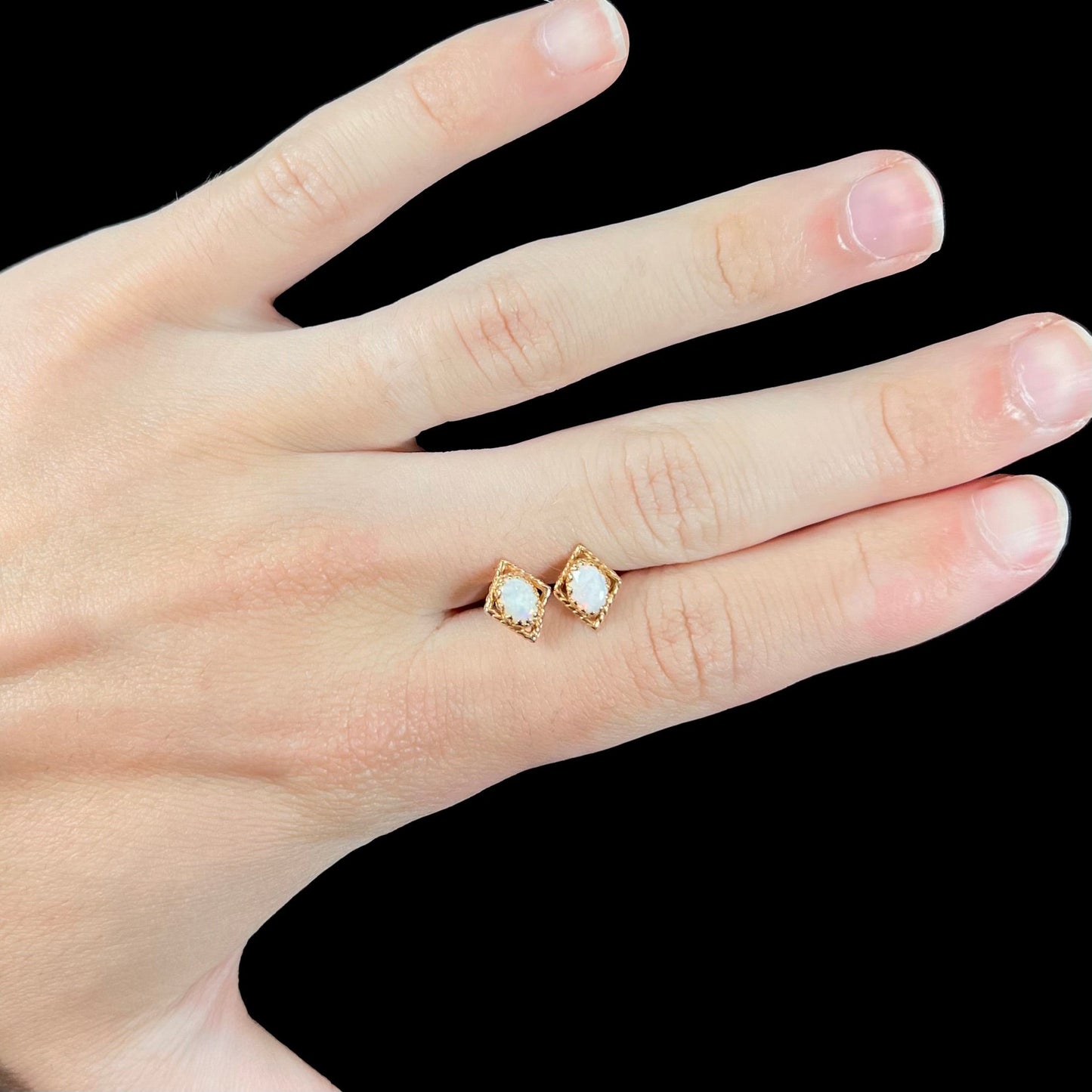 A pair of opal stud earrings. The opals are set in yellow gold diamond shaped mountings.