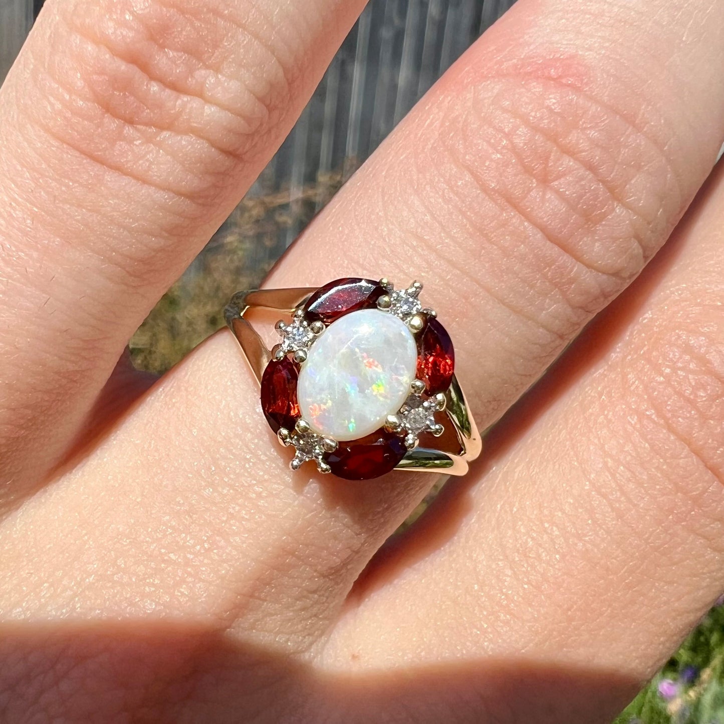 A ladies natural opal ring in yellow gold. The opal is surrounded by red marquise cut garnets and diamonds.