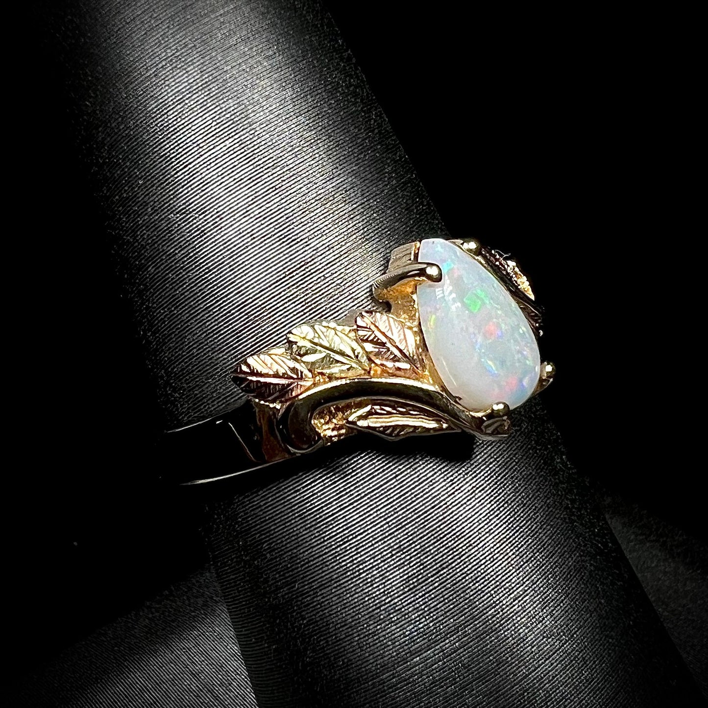 A ladies' two-tone yellow and rose Black Hills gold opal and diamond ring. The opal is a pear shaped cabochon.