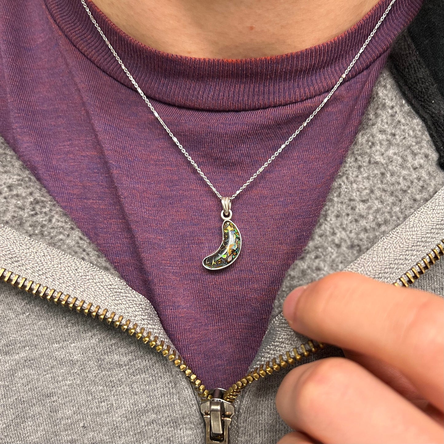 A sterling silver necklace bezel set with a natural Koroit boulder opal stone. The stone is shaped like a crescent moon.
