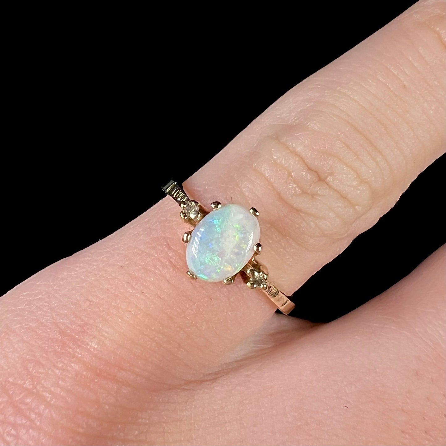 A dainty, 1960's style opal and diamond engagement ring. The ring is prong-set and yellow gold.