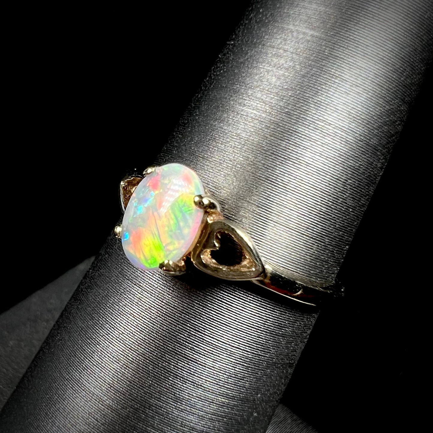 A dainty yellow gold ring mounted with a vivdly bright red Australian opal. The ring has two heart shaped designs.