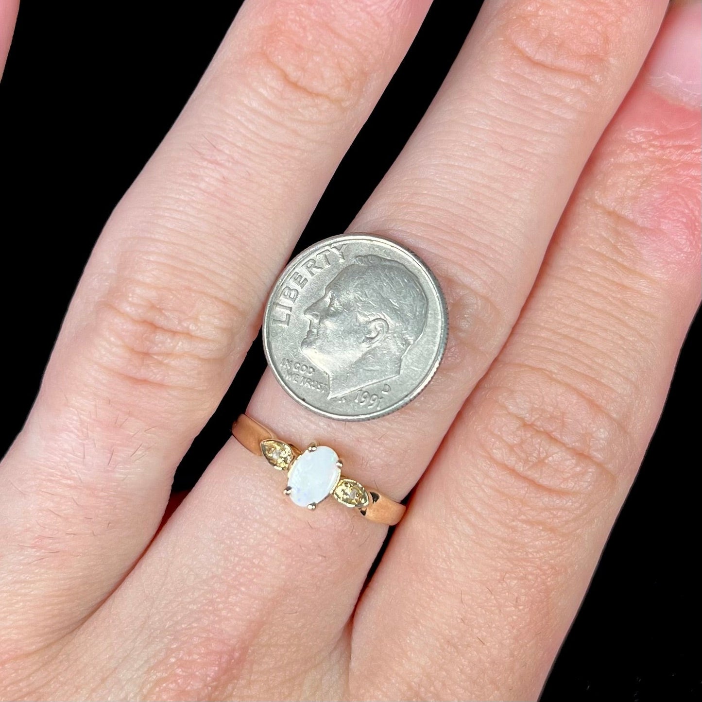 A dainty ladies' yellow gold opal and diamond ring. The opal has subtle play of color.