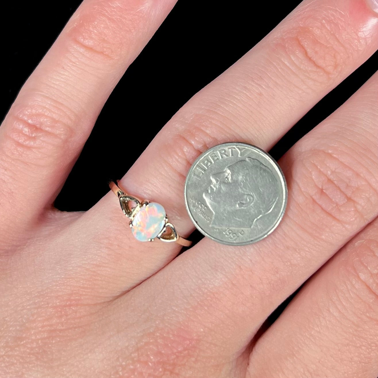 A dainty yellow gold ring mounted with a vivdly bright red Australian opal. The ring has two heart shaped designs.