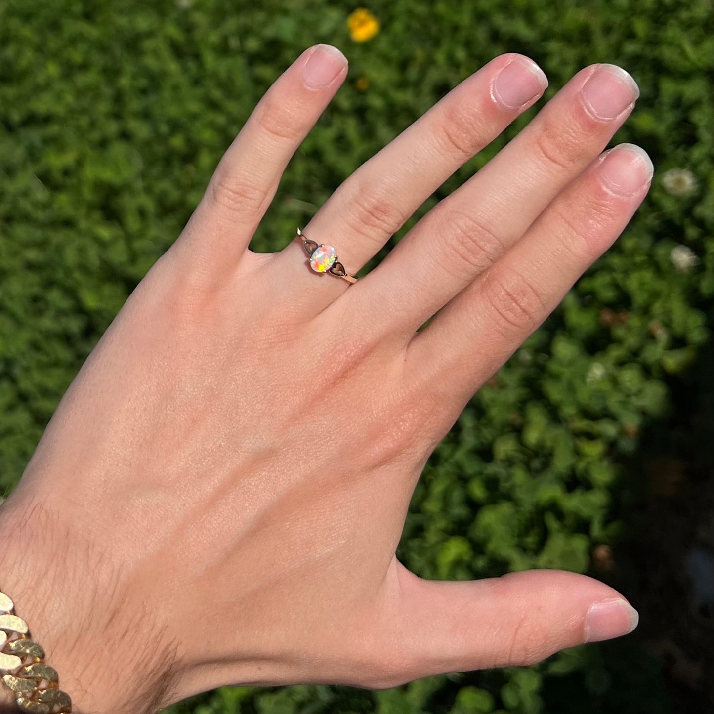 A dainty yellow gold ring mounted with a vivdly bright red Australian opal. The ring has two heart shaped designs.