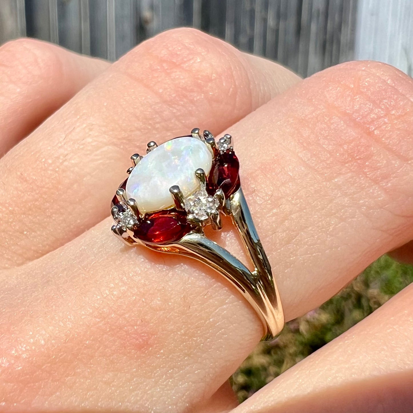 A ladies natural opal ring in yellow gold. The opal is surrounded by red marquise cut garnets and diamonds.