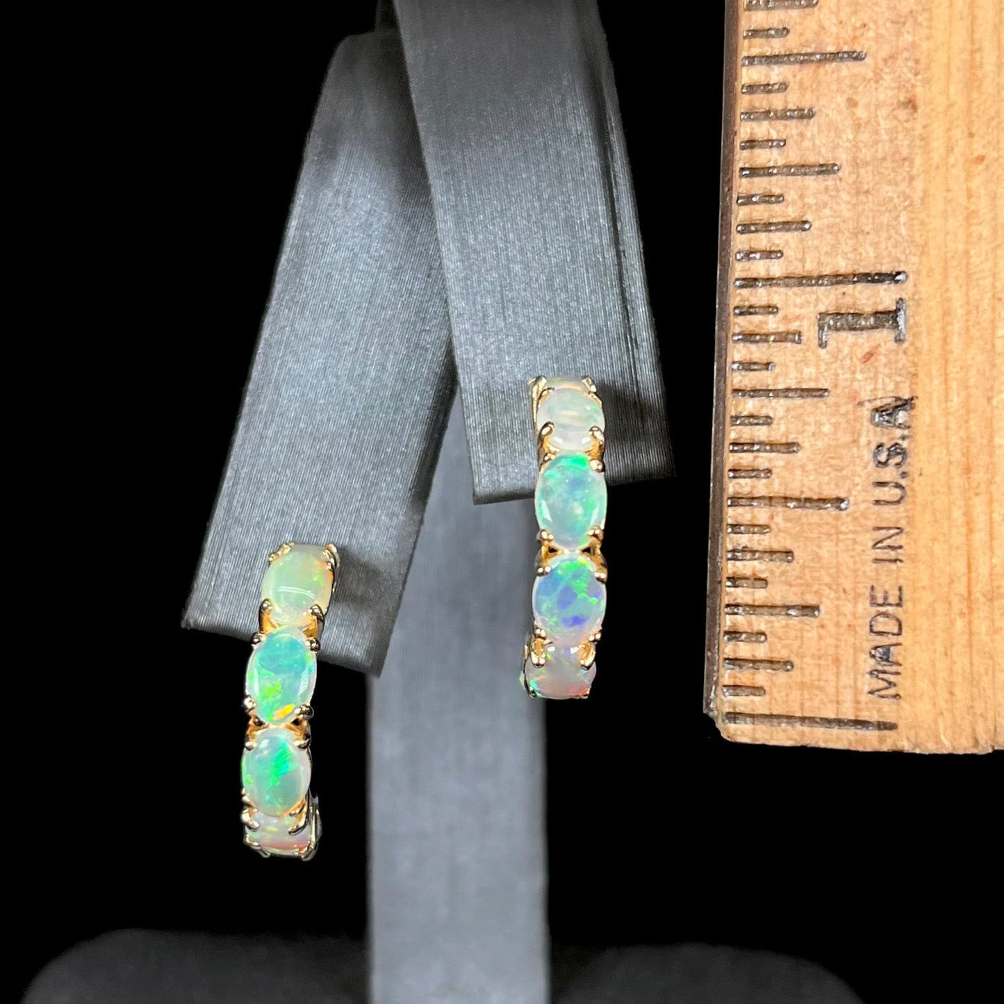 A pair of yellow gold opal hoop earrings. Each earring is set with six natural oval cut opals.