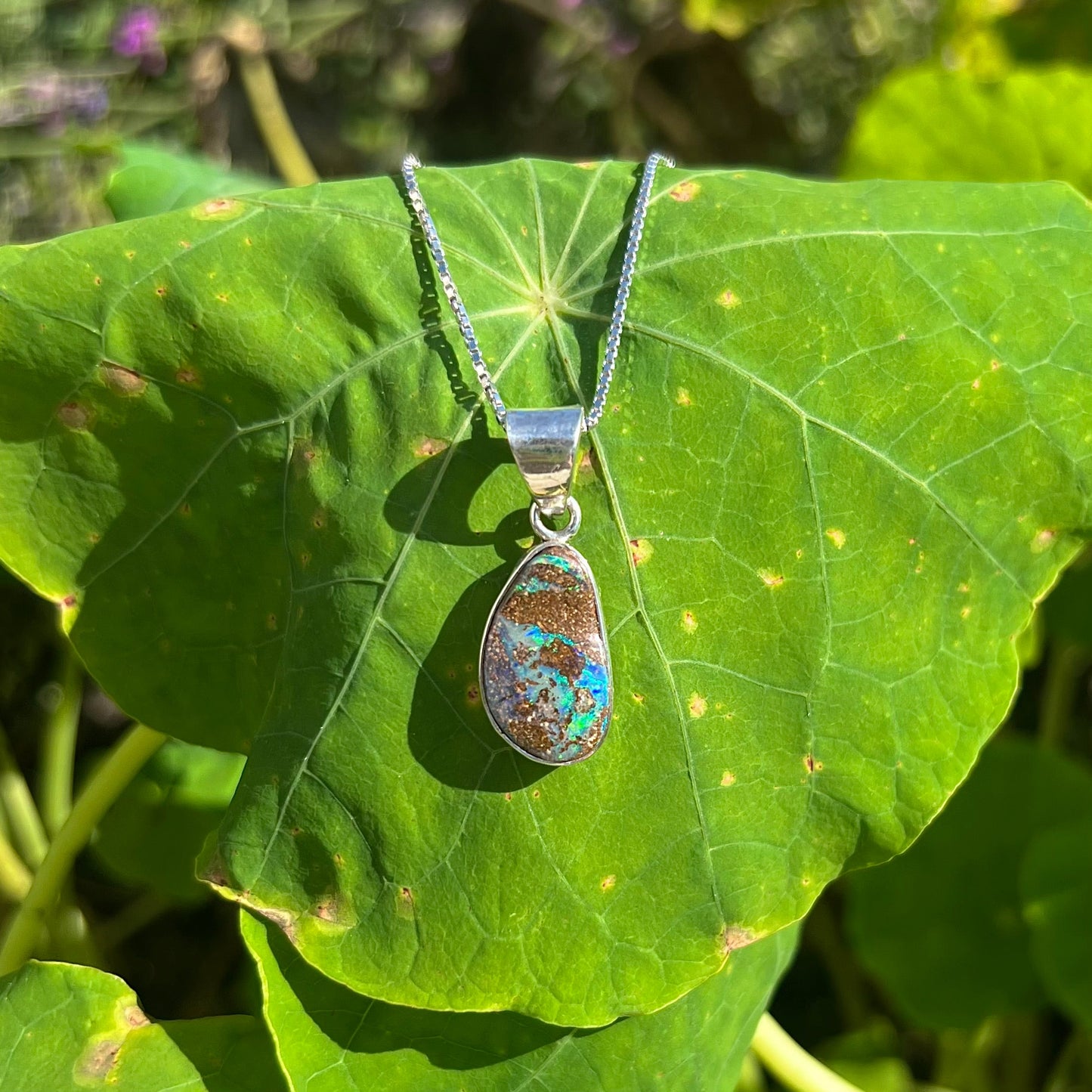 A sterling silver necklace set with a rainbow boulder opal stone.