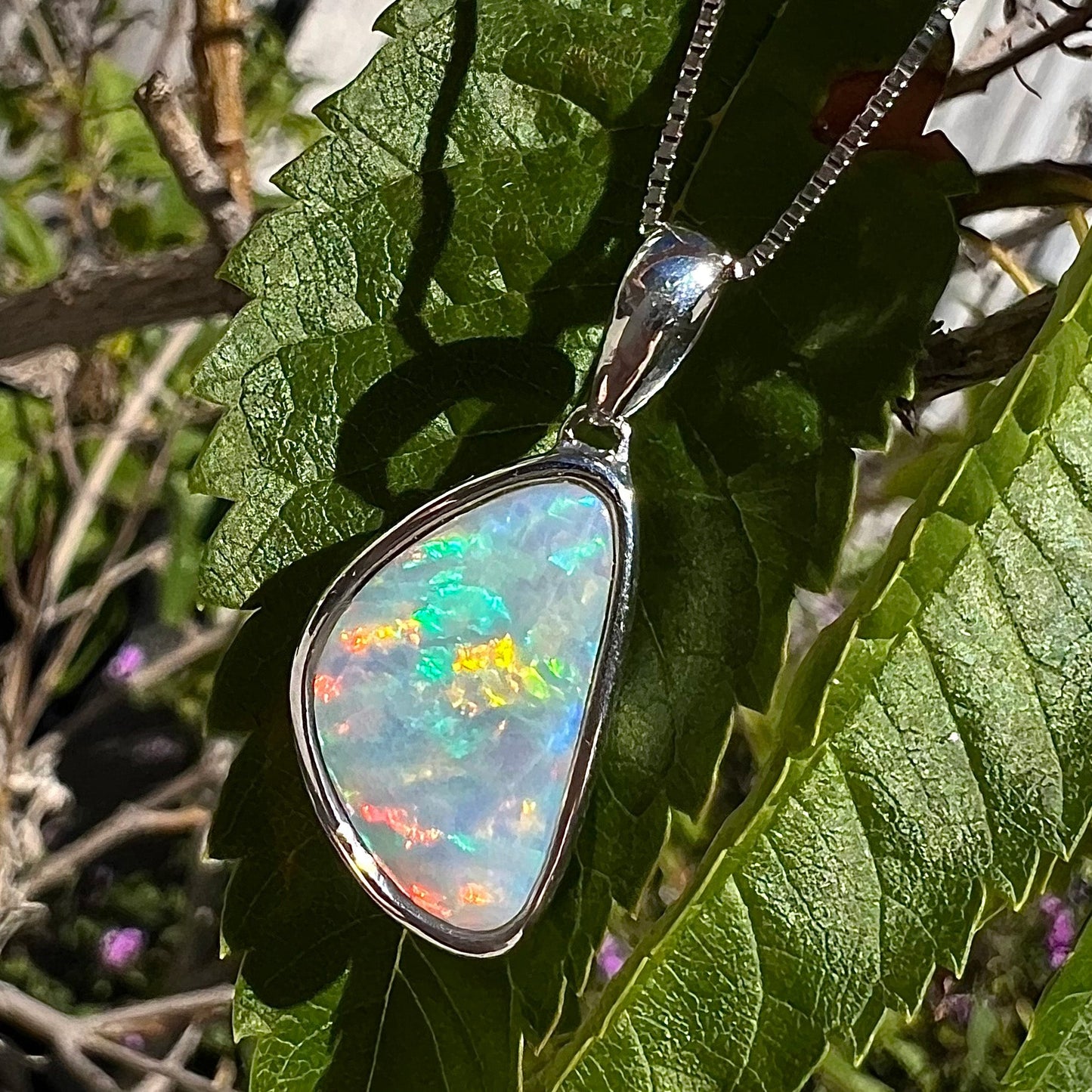 A sterling silver pendant bezel set with a white Australian crystal opal on a box chain.