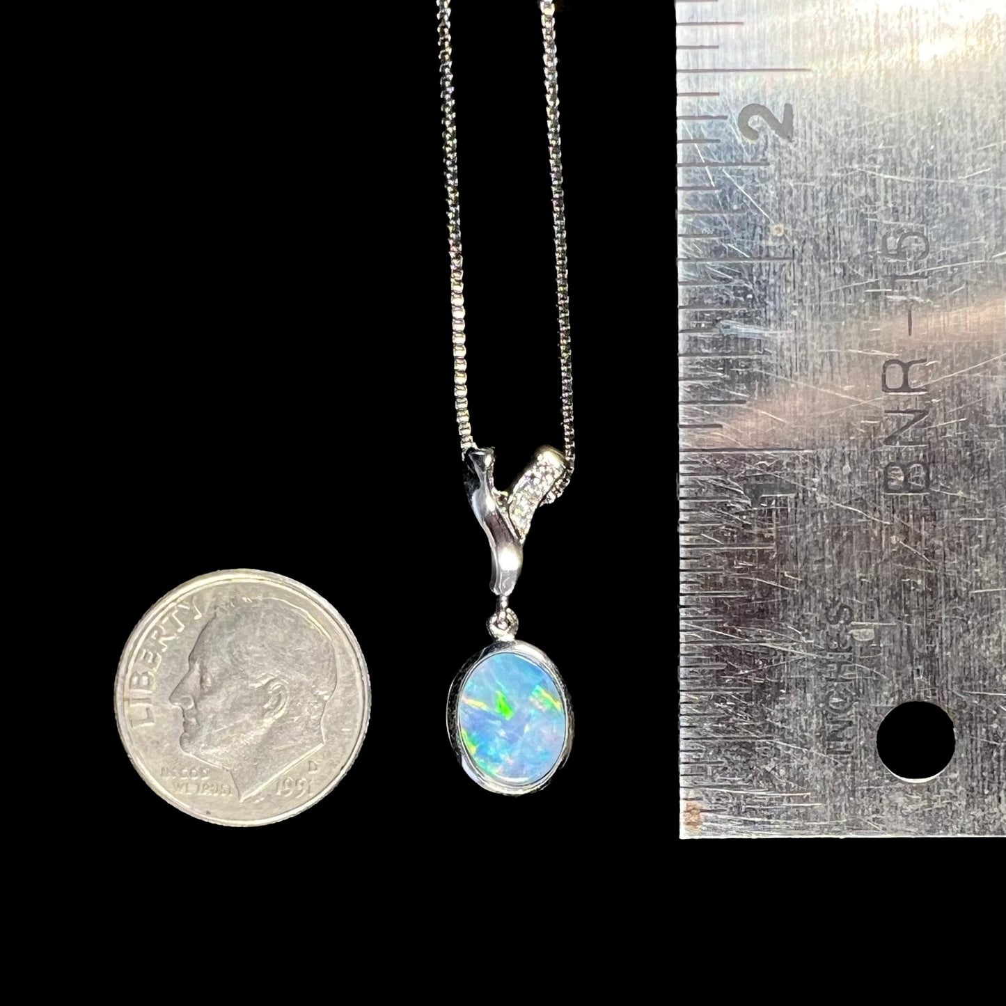 A sterling silver necklace set with a natural black opal doublet and white zircon accent stones.