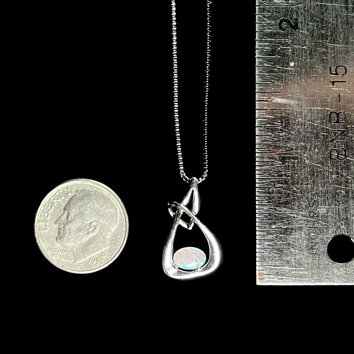 A ladies' sterling silver pendant set with an oval cabochon cut natural white crystal opal.