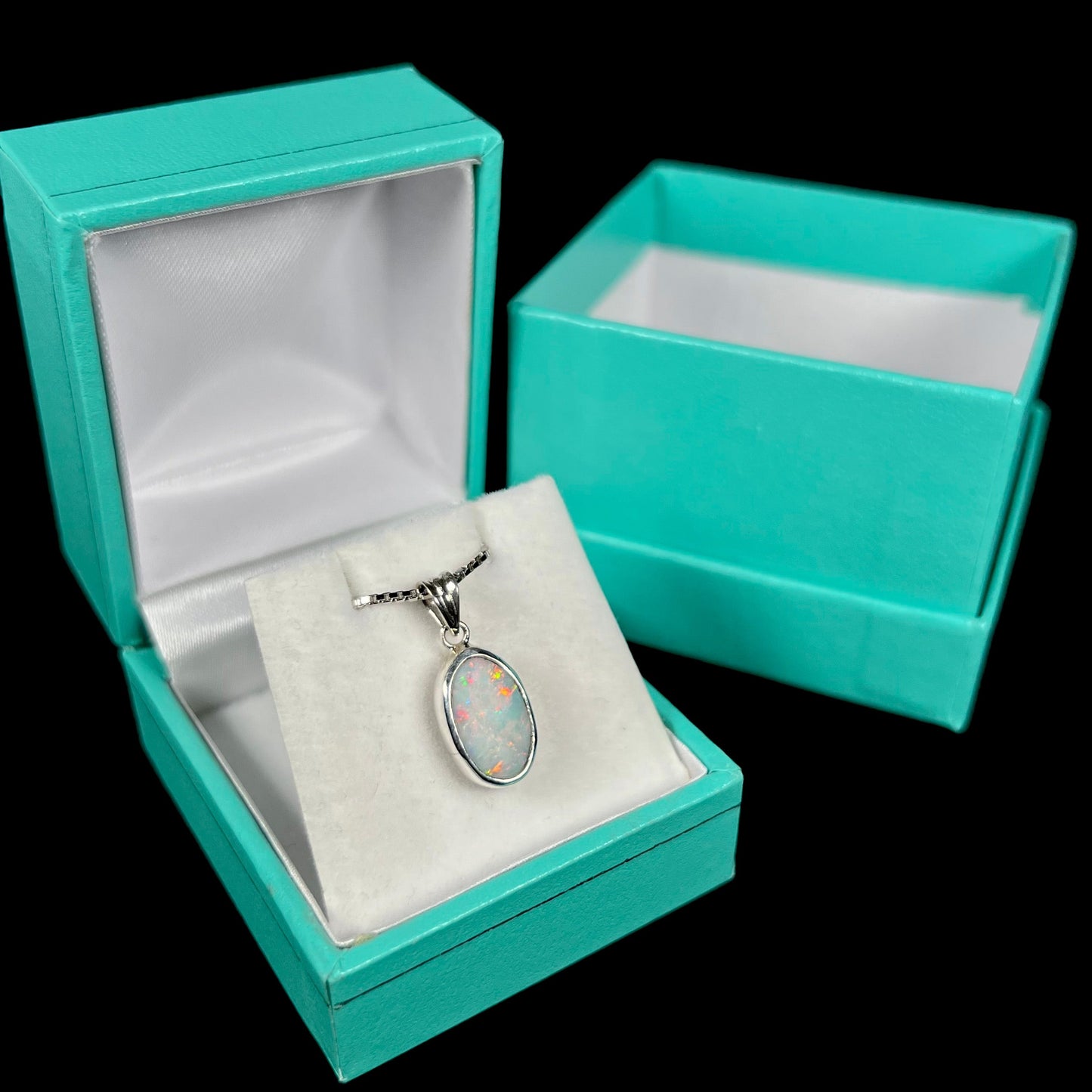 A ladies' sterling silver necklace bezel set with a natural white crystal opal. The opal has red and blue fire.