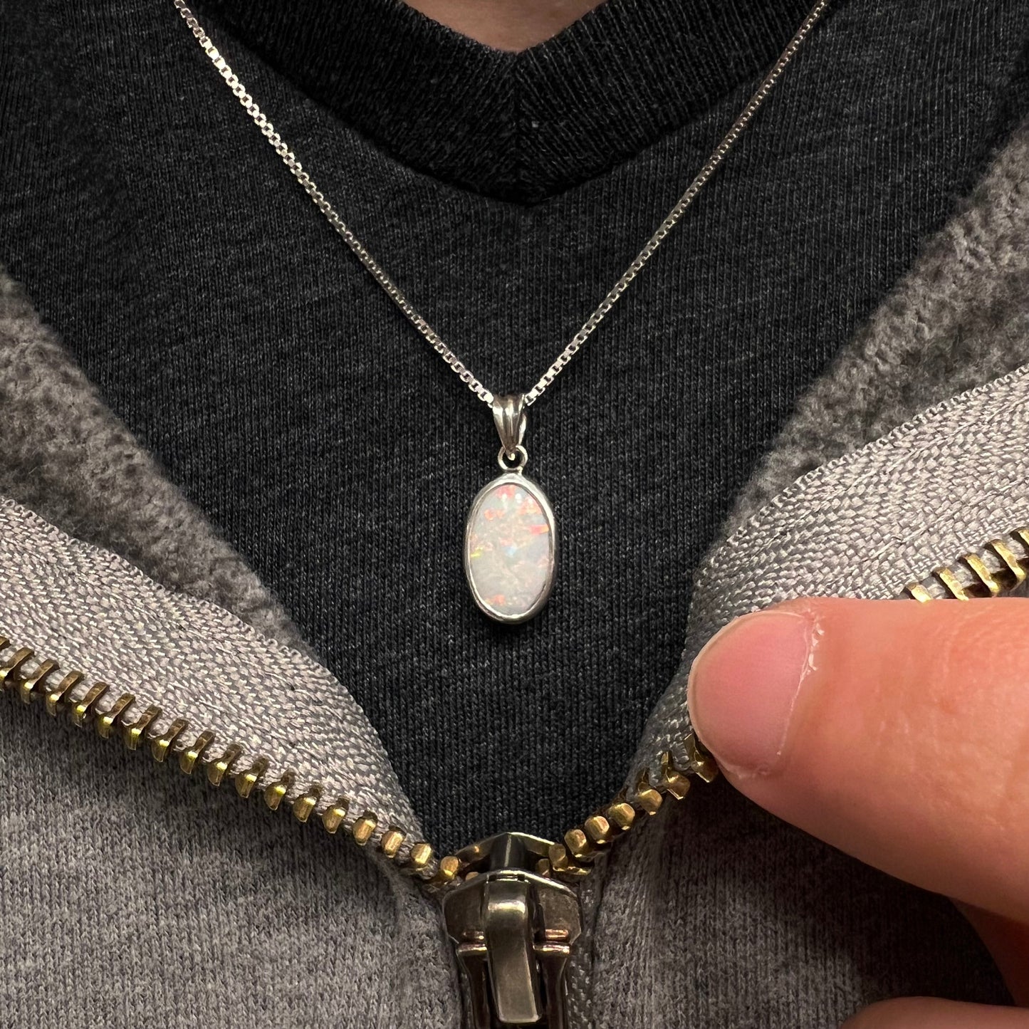 A ladies' sterling silver necklace bezel set with a natural white crystal opal. The opal has red and blue fire.