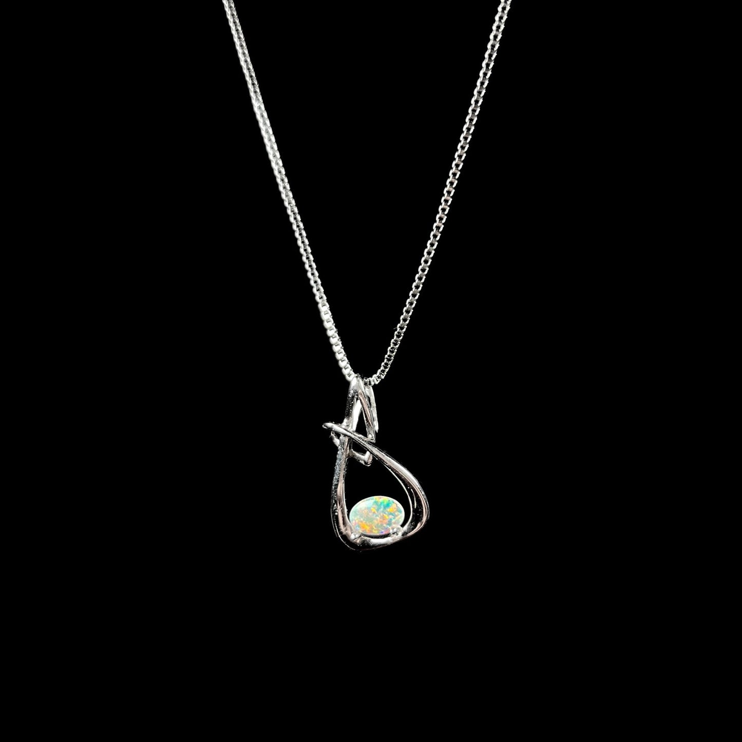 A ladies' sterling silver pendant set with an oval cabochon cut natural white crystal opal.
