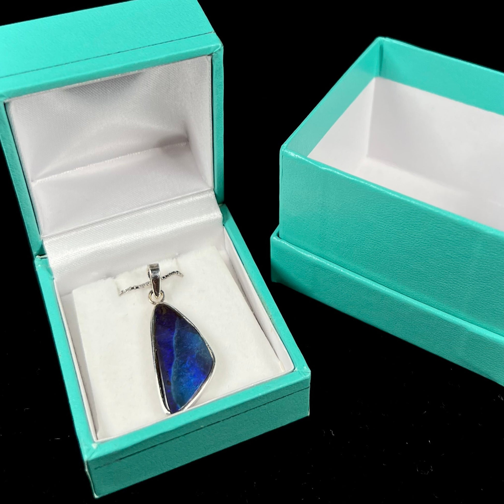 A ladies' sterling silver necklace bezel set with a triangle drop shaped Australian black boulder opal.