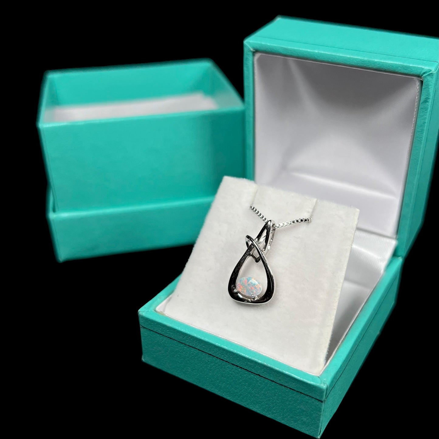 A ladies' sterling silver pendant set with an oval cabochon cut natural white crystal opal.
