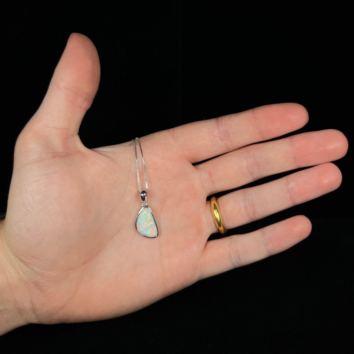 A sterling silver pendant bezel set with a white Australian crystal opal on a box chain.