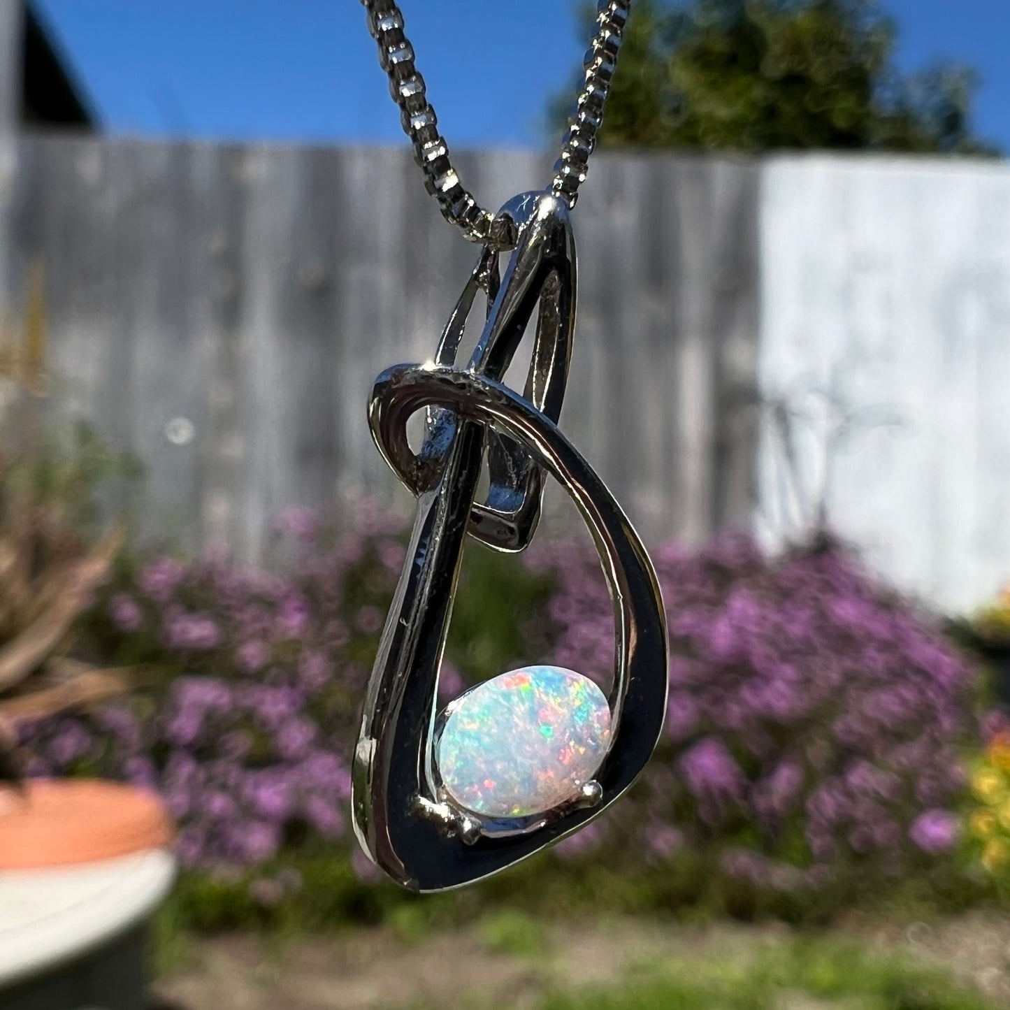 A ladies' sterling silver pendant set with an oval cabochon cut natural white crystal opal.