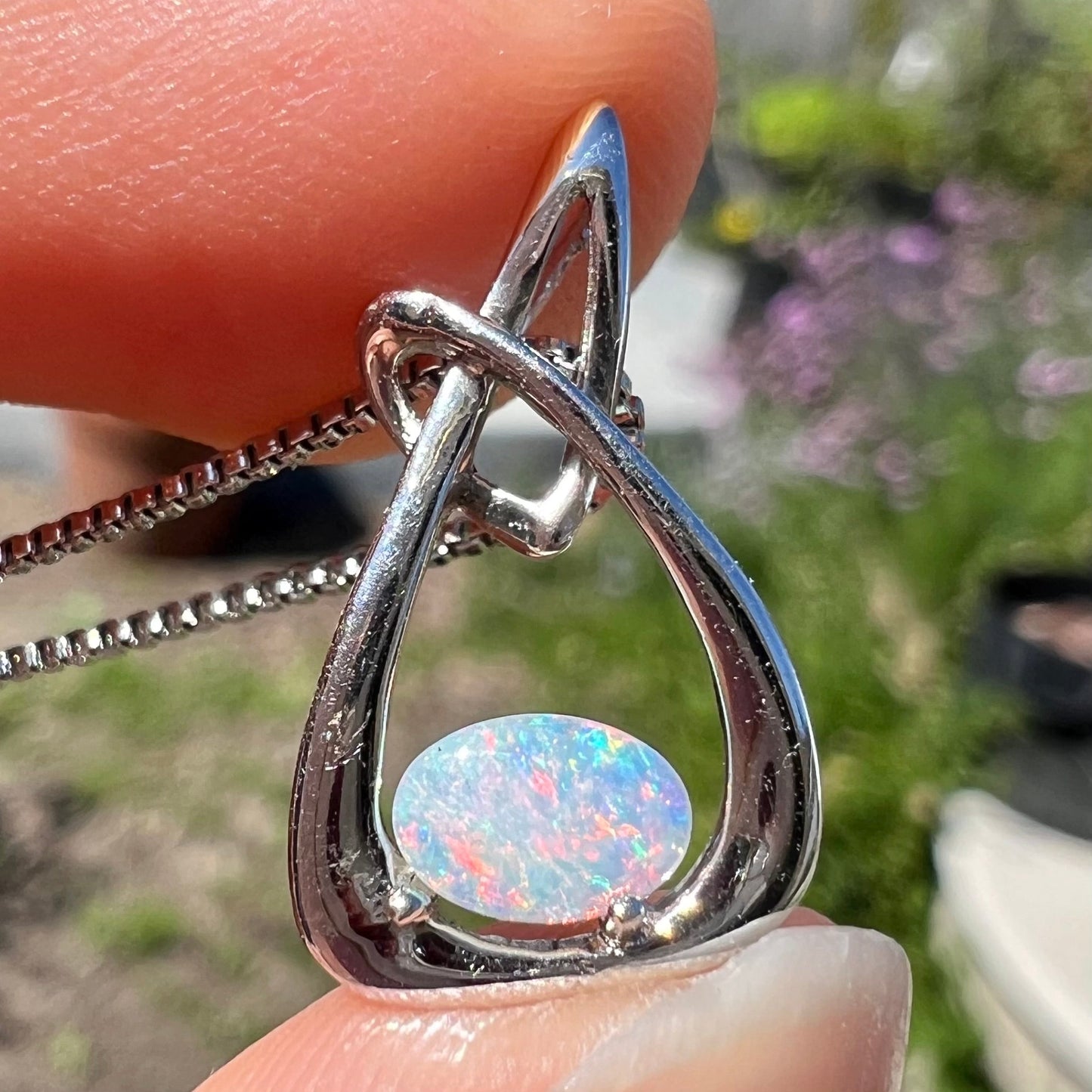 A ladies' sterling silver pendant set with an oval cabochon cut natural white crystal opal.