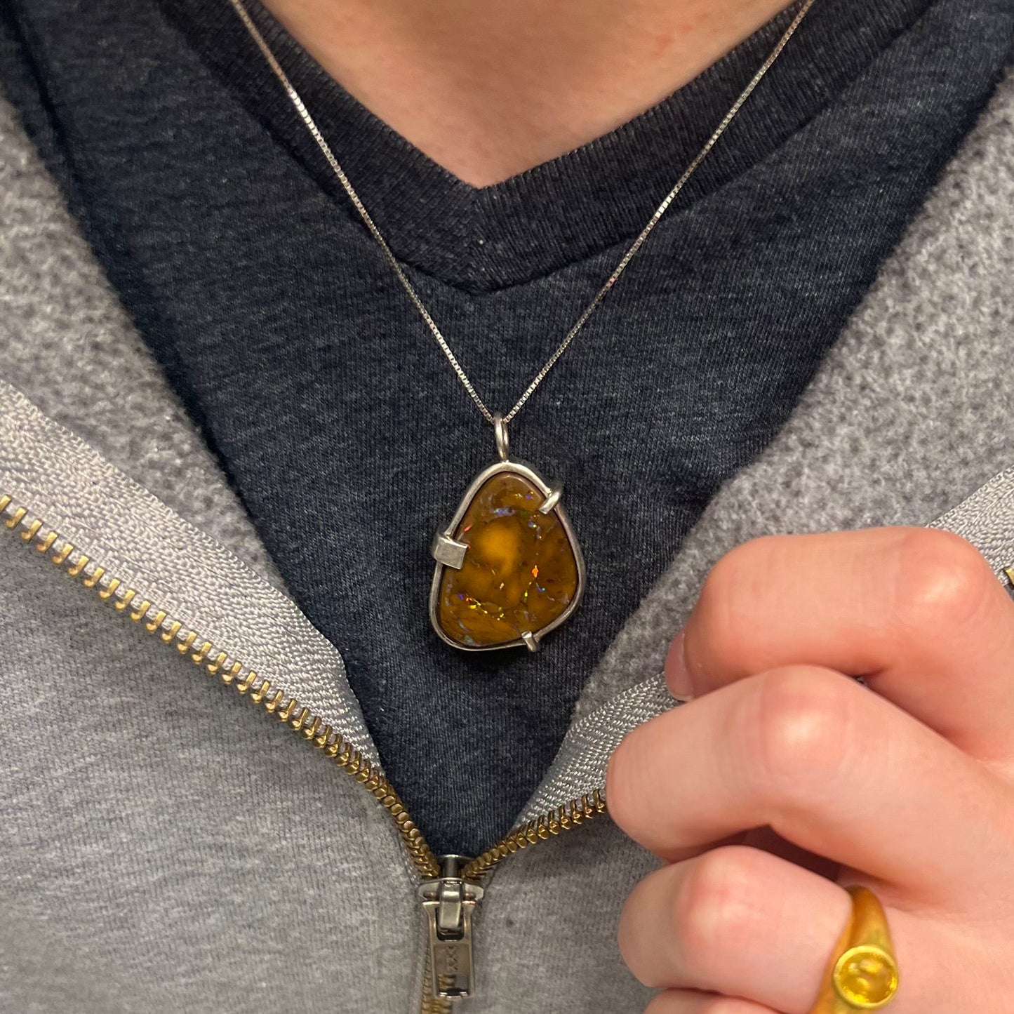 A handmade sterling silver pendant bezel and prong set with a natural boulder opal stone. The opal shines veins of color.
