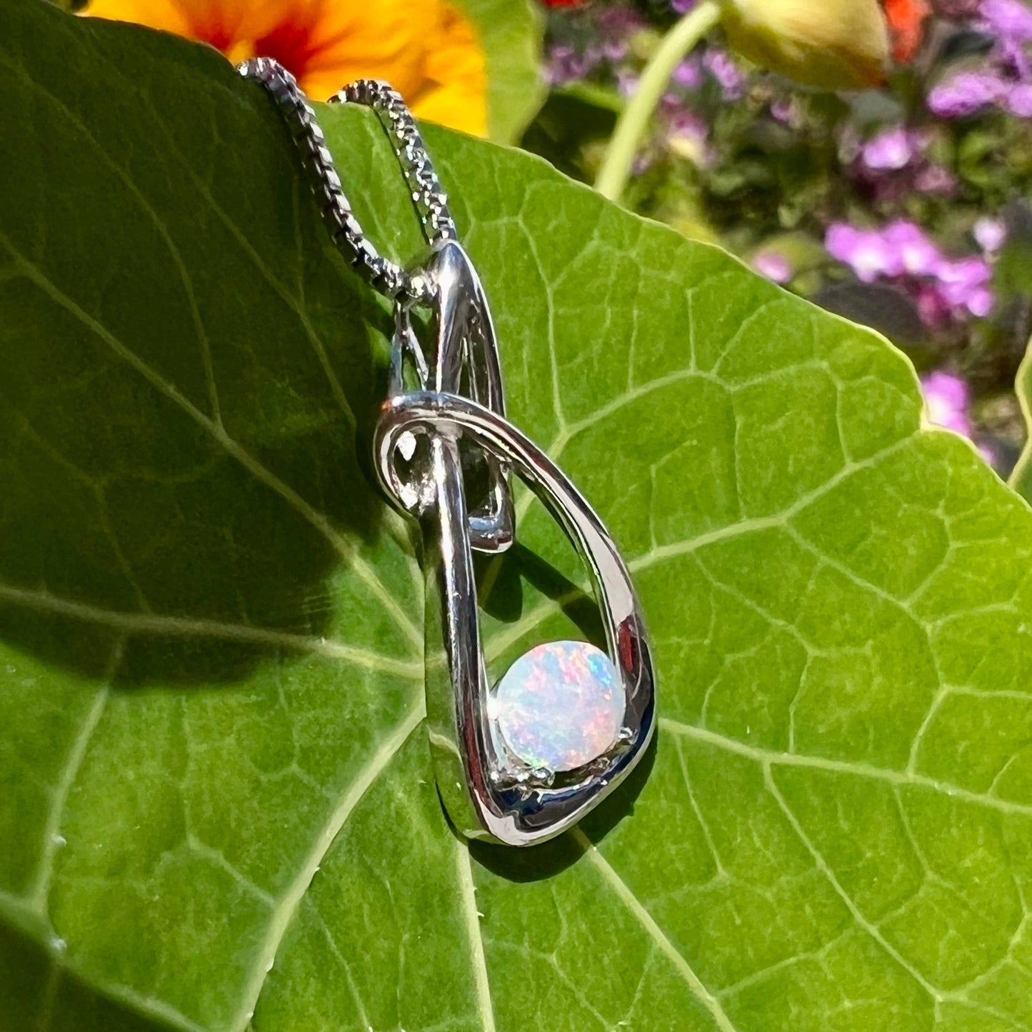 A ladies' sterling silver pendant set with an oval cabochon cut natural white crystal opal.