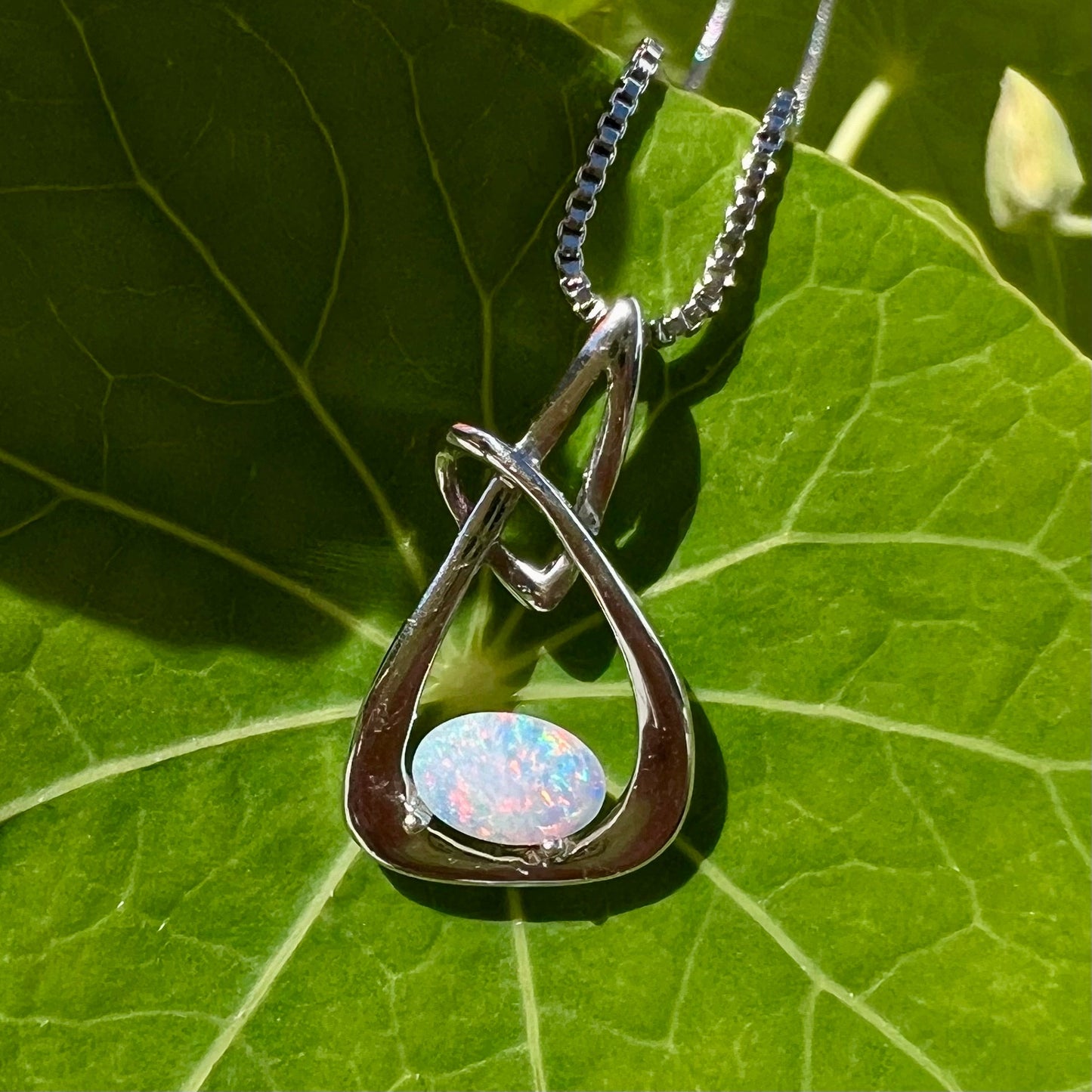 A ladies' sterling silver pendant set with an oval cabochon cut natural white crystal opal.