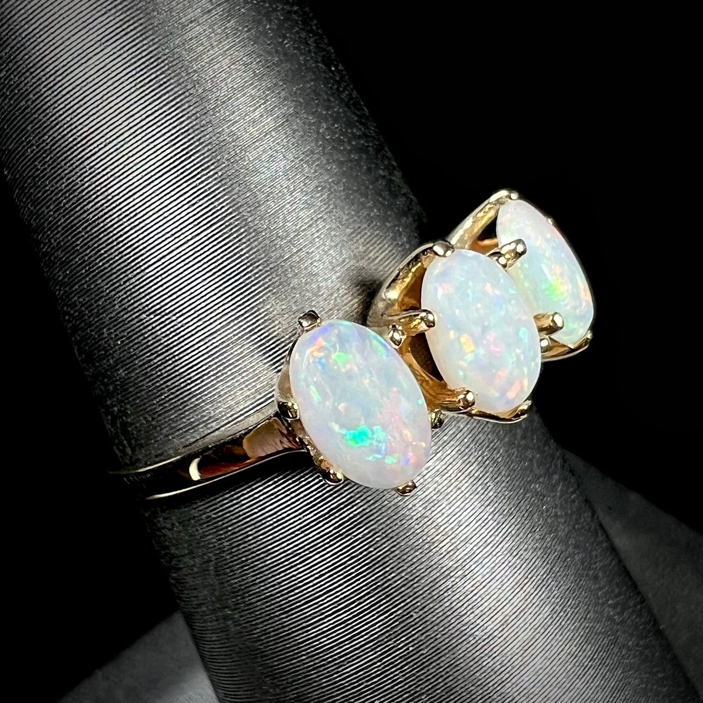 A vintage yellow gold ring mounted with three oval cut white Australian opals.