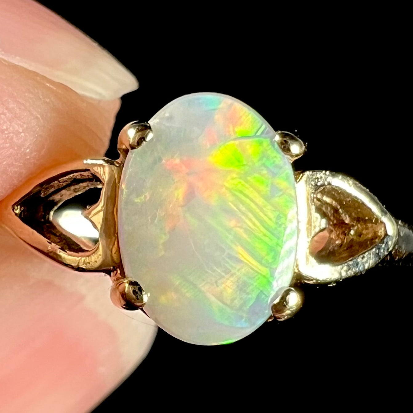 A dainty yellow gold ring mounted with a vivdly bright red Australian opal. The ring has two heart shaped designs.