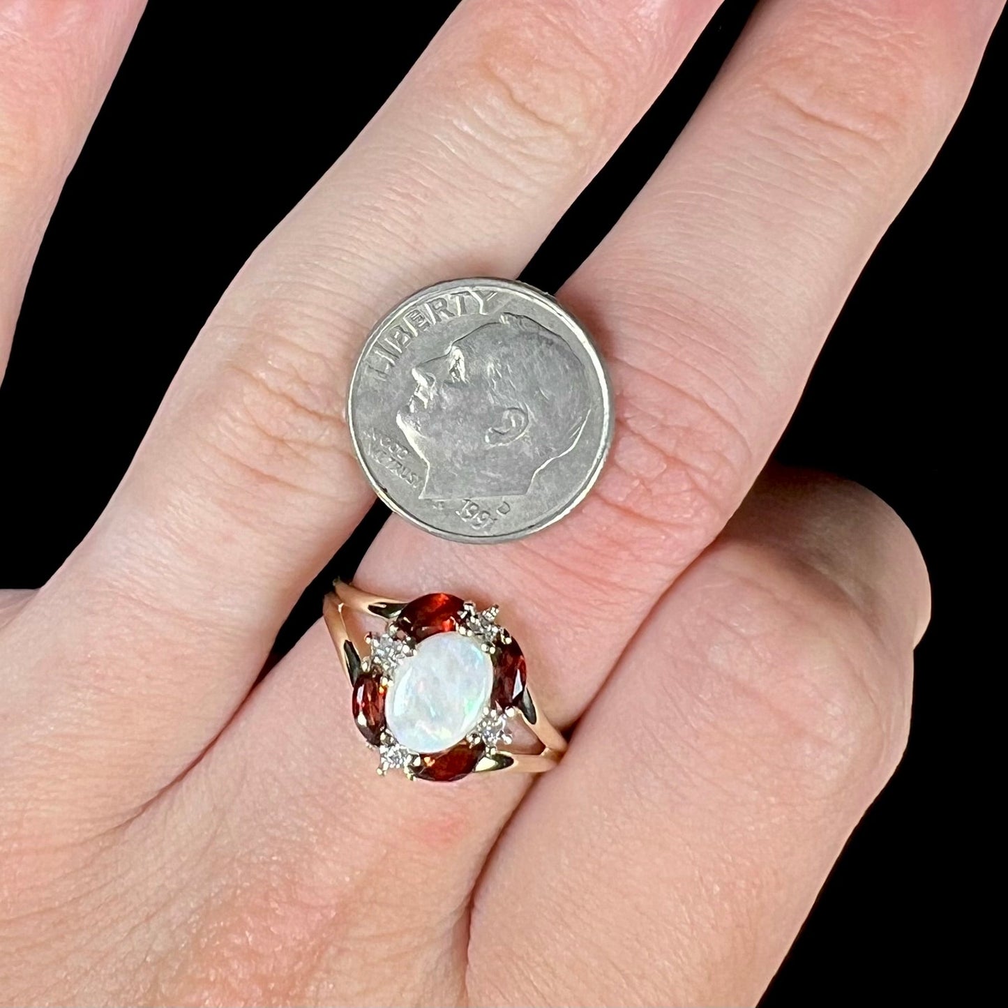 A ladies natural opal ring in yellow gold. The opal is surrounded by red marquise cut garnets and diamonds.