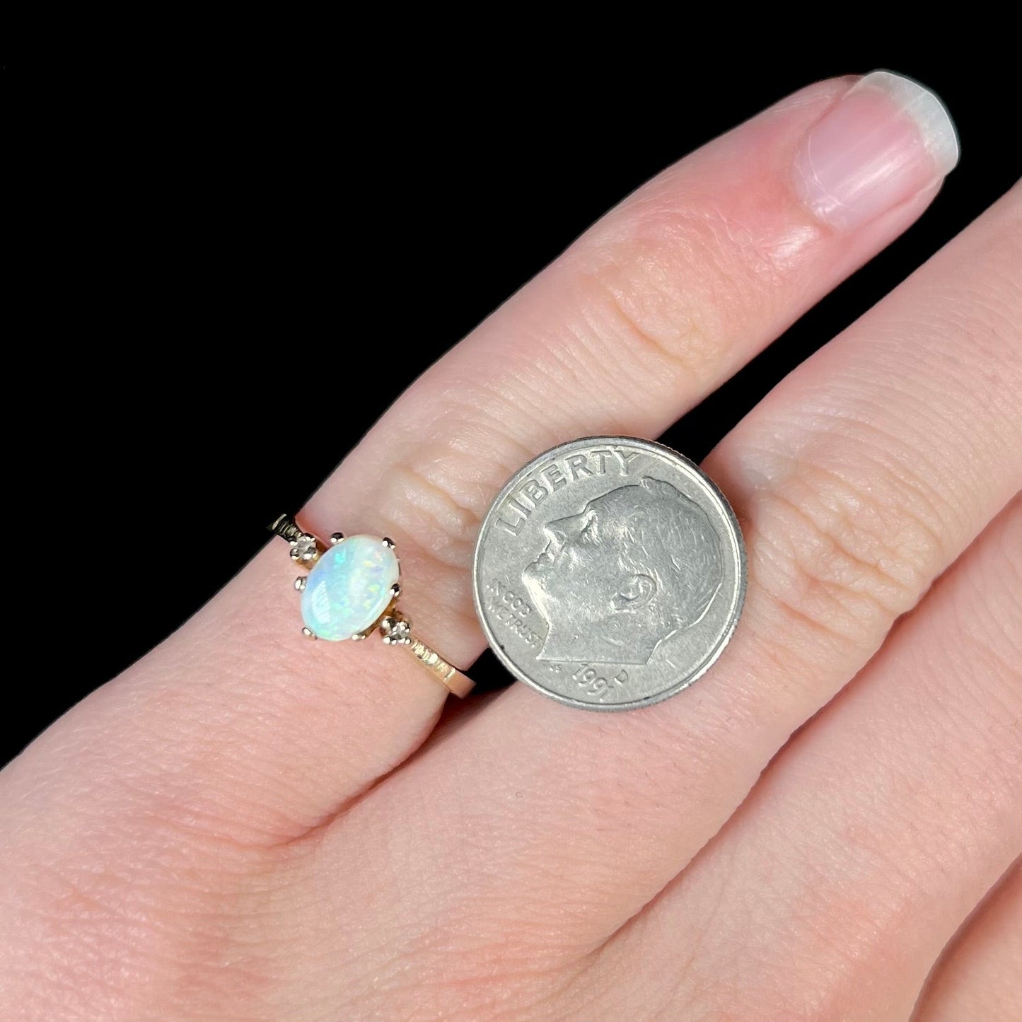 A dainty, 1960's style opal and diamond engagement ring. The ring is prong-set and yellow gold.